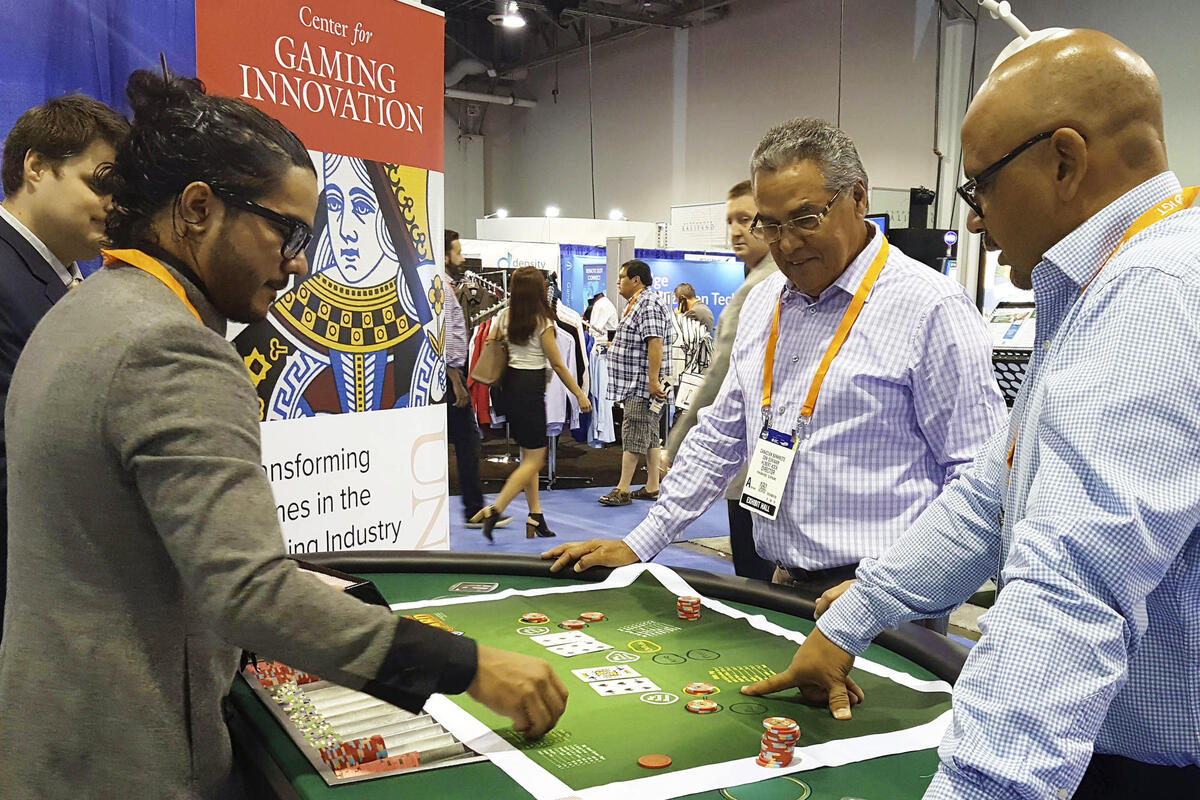 Aron Kock demonstrates his blackjack variant to two onlookers at a gaming convention.
