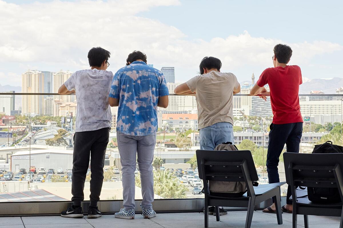 Four students looking over balcony.