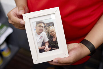 a man holds a framed photo of himself with his grandmother