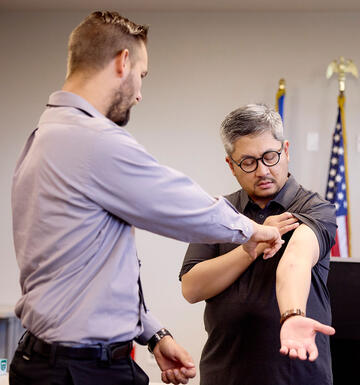 a man shows scars on his arm to another man