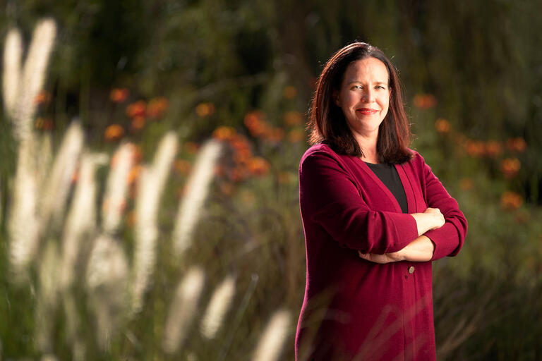 Tracy Spies poses in front of flowers and bushes.