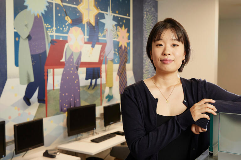 A woman sits next to a mural