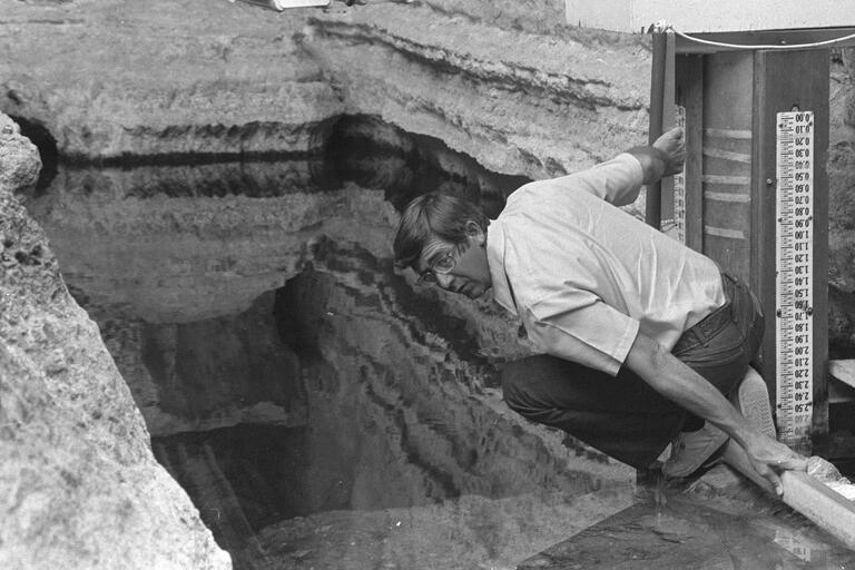 archival photo of man peering into water